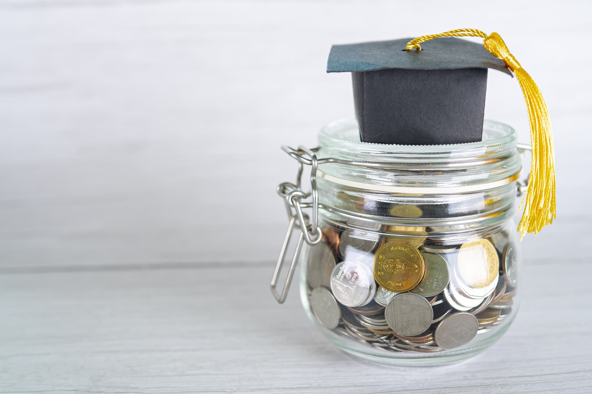 A jar of coins with a small graduation hat on top.