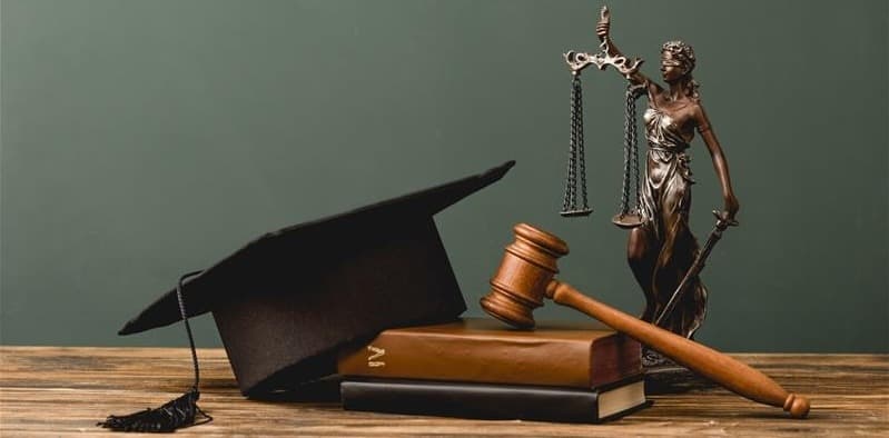 A scale and a pile of books with a graduation cap on top.